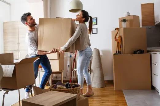 Couple transportant un carton dans un logement en déménagement