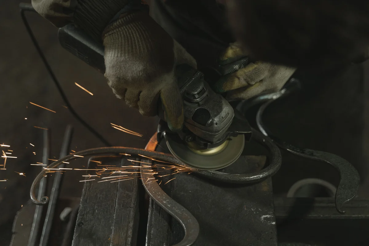 Découpe d’une pièce métallique à la meuleuse avec des gants de protection