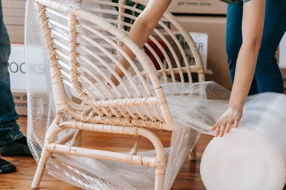 Une chaise en rotin est protégée avec du film à bulles avant son transport.